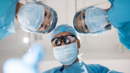 A low angle shot of surgeons looking at you on the operating table